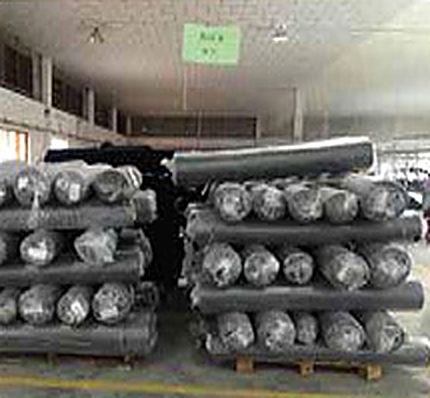 Rolls of denim stacked on pallets in a warehouse