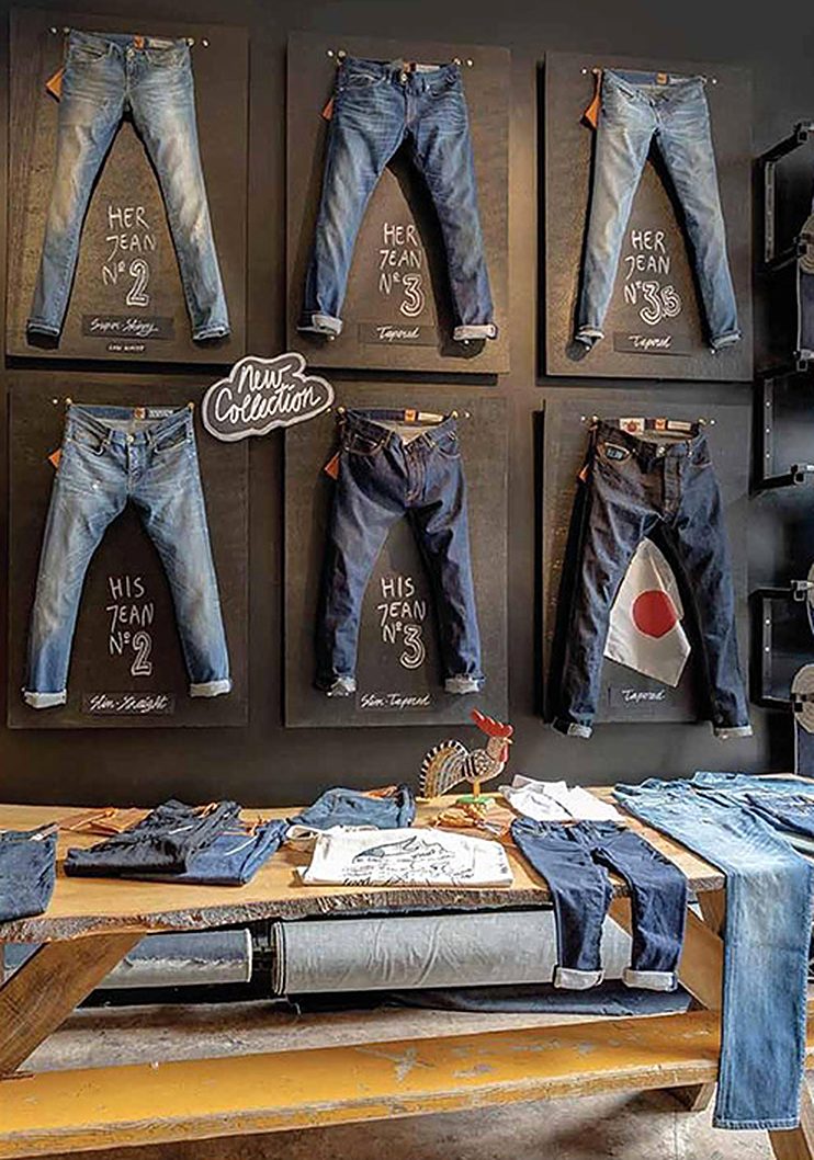 Showroom wall of jeans on boards above a table of folded denim