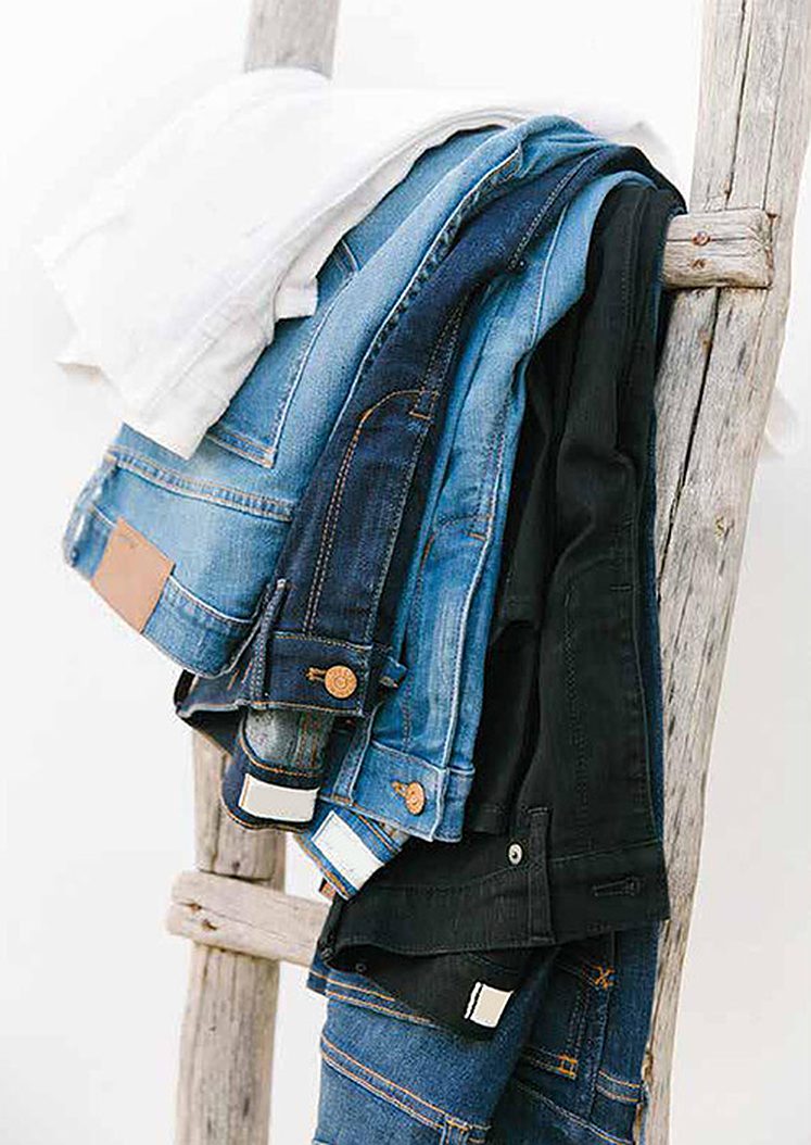 Jeans in several washes hanging over a wooden ladder