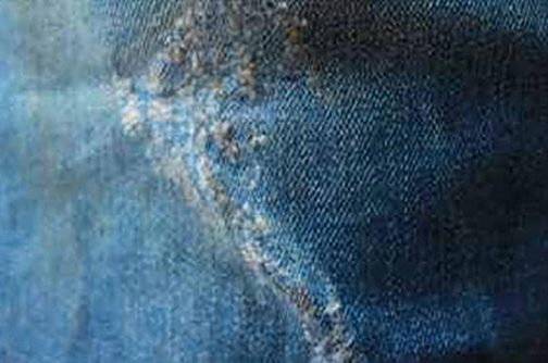 Close-up of light blue washed denim, worn along a seam